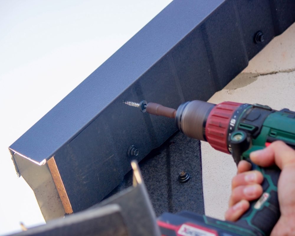 a man repairs the roof, tightens the self-tapping screw with a screwdriver. Selective focus